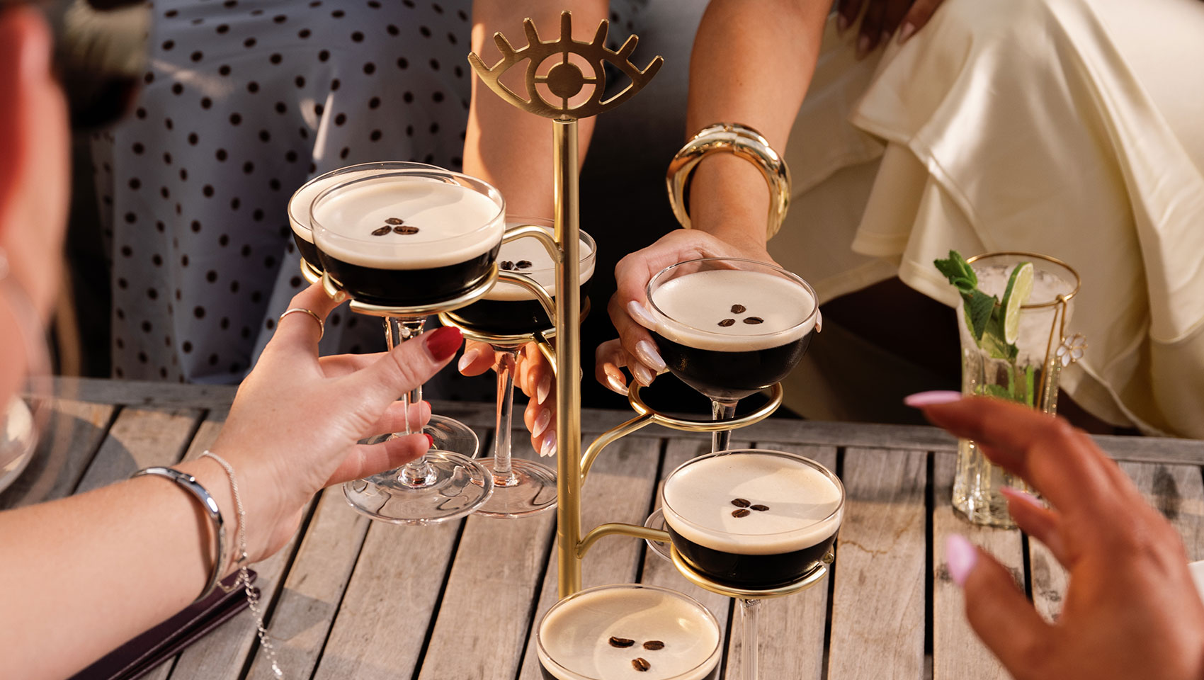 woman's hand holding a photo of people toasting with cocktails on her phone