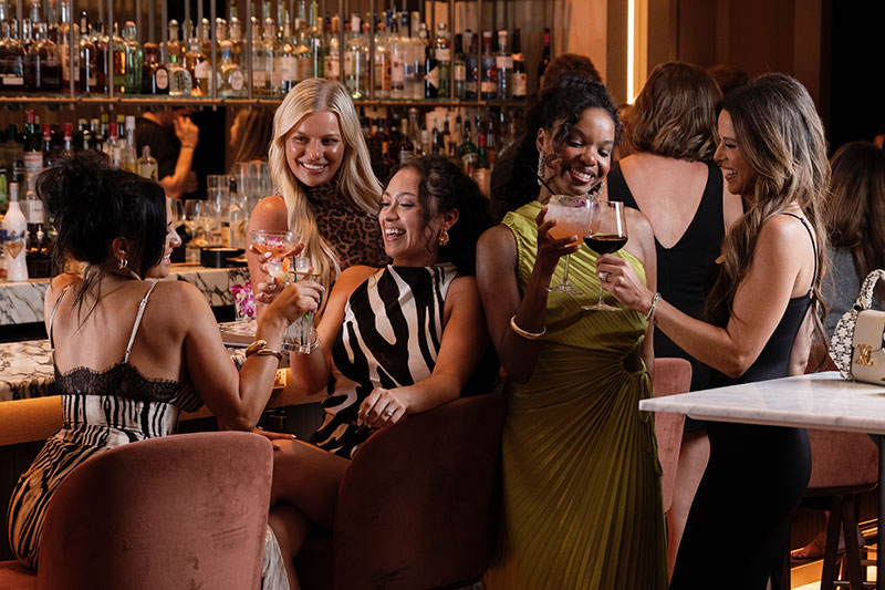 Guests toasting cocktails at Astrea bar